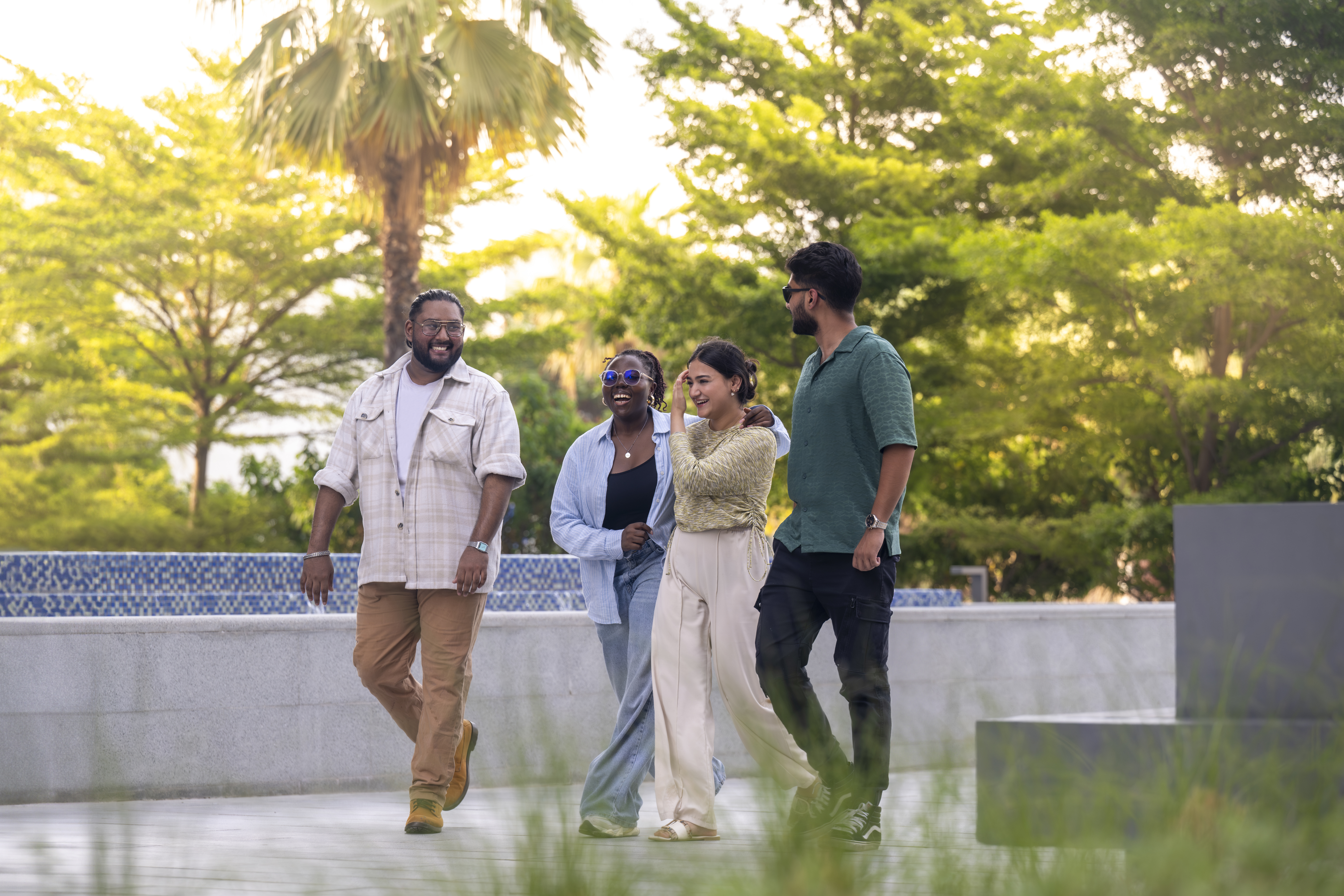 Four smiling young people walking, palm trees in the background