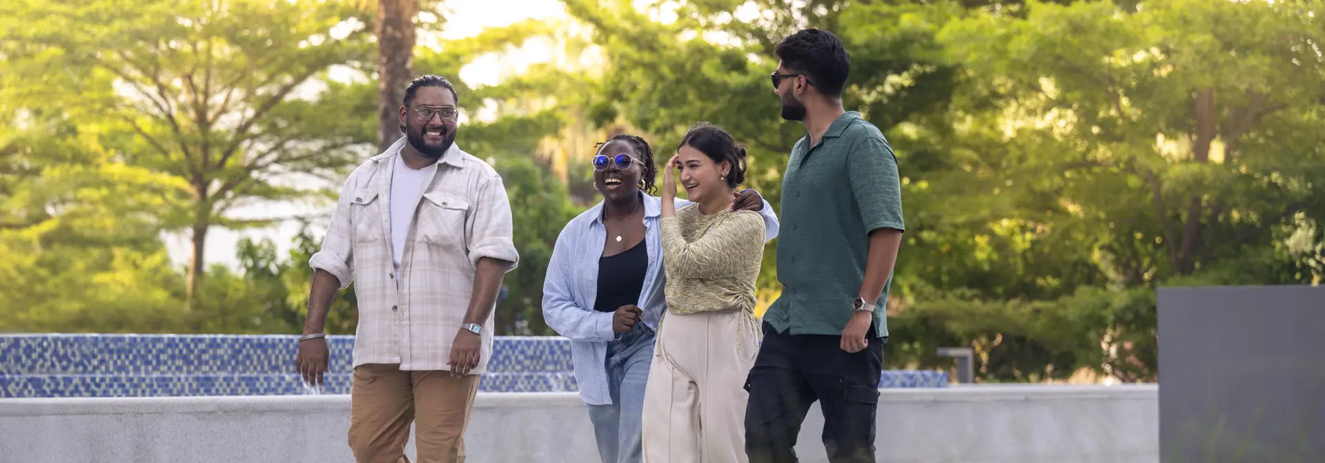 Four smiling young people walking, palm trees in the background