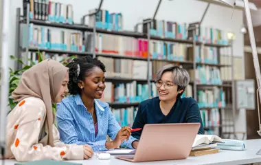 Three students working together in a library