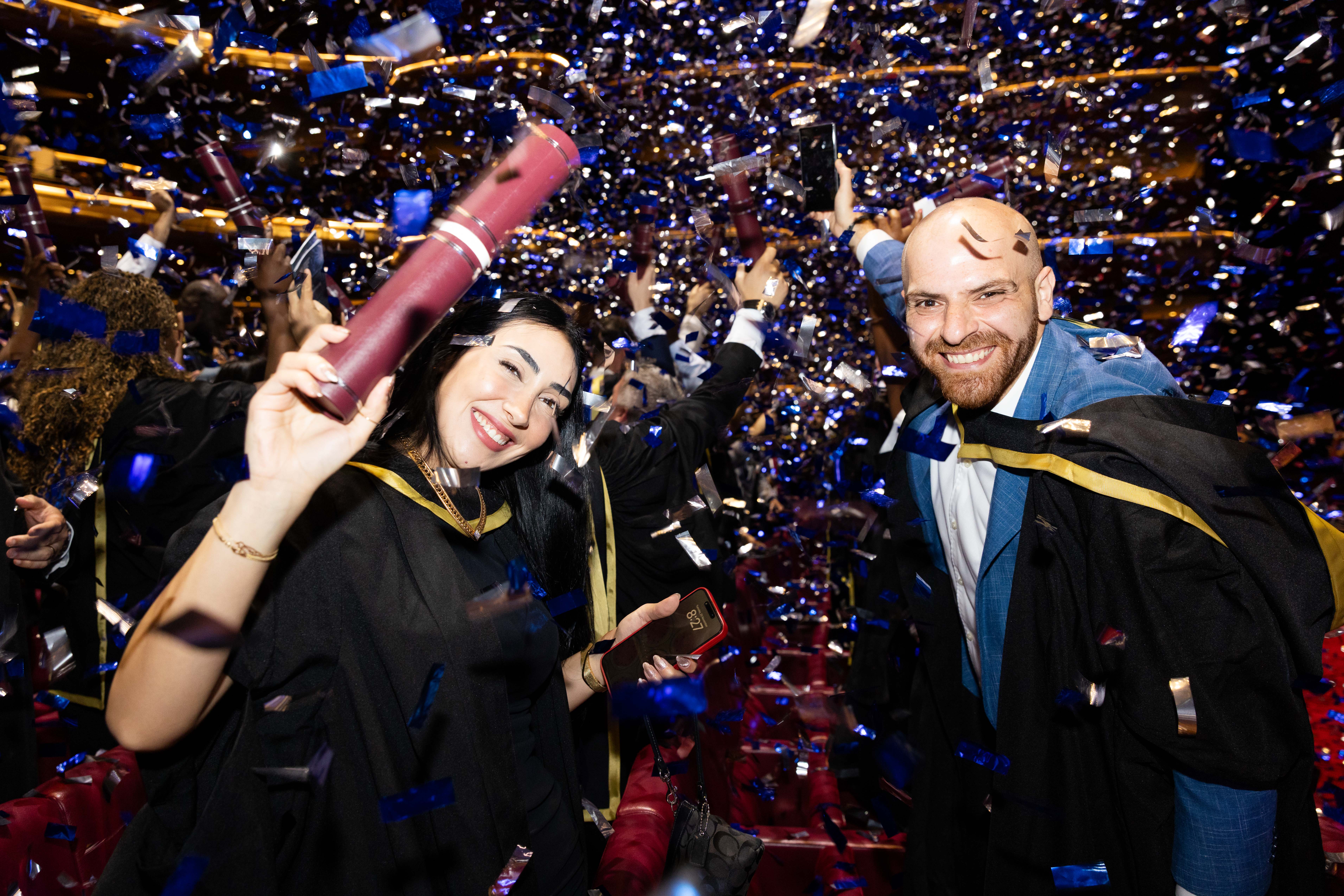 students celebrating and showing scrolls during the confetti at graduation ceremony