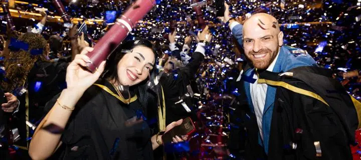 students celebrating and showing scrolls during the confetti at graduation ceremony