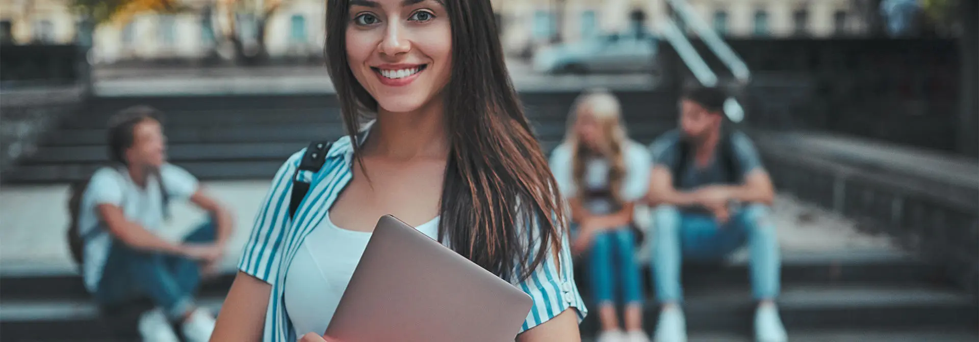 A woman holding a laptop smiling