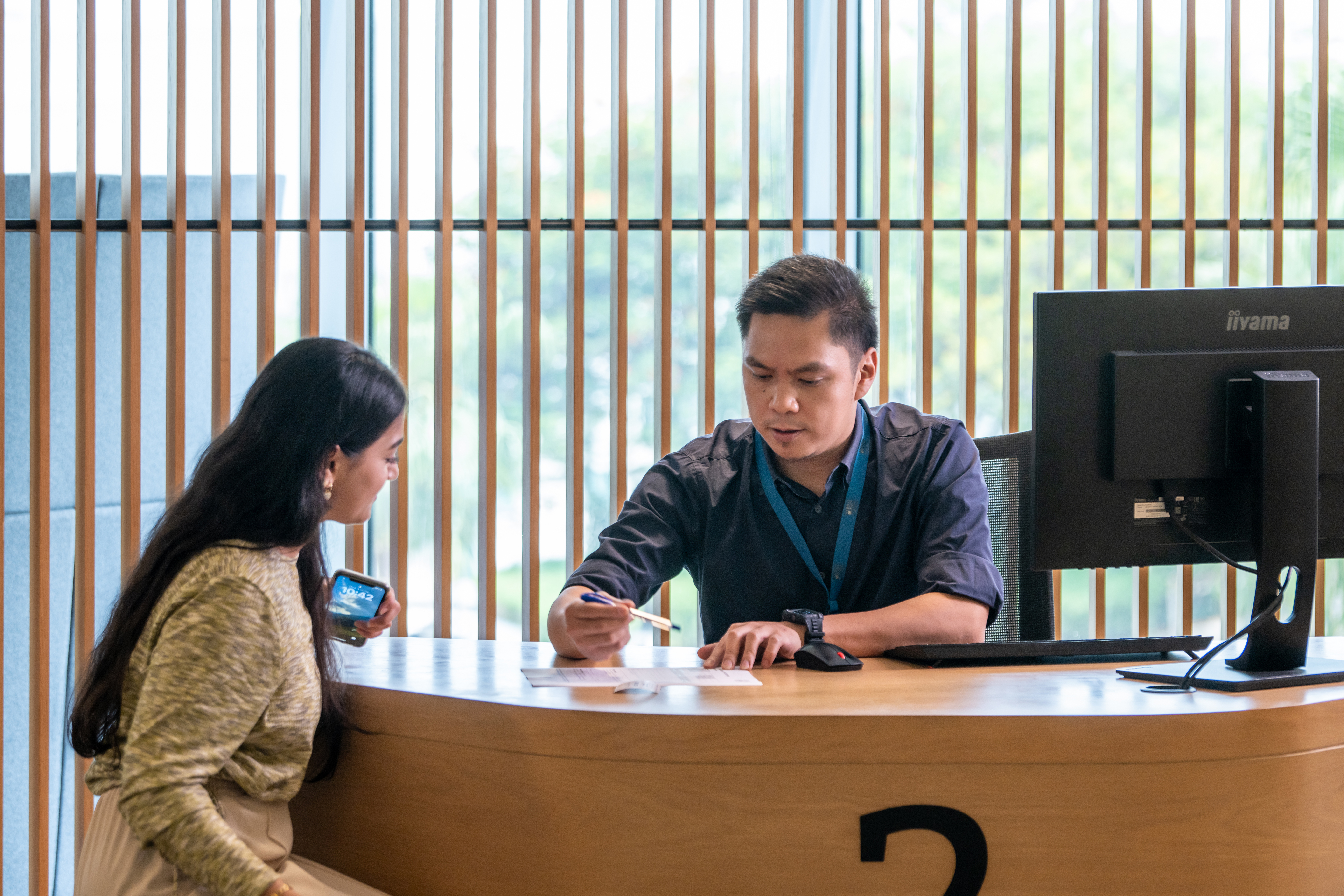 Individual helping a student from across a computer desk
