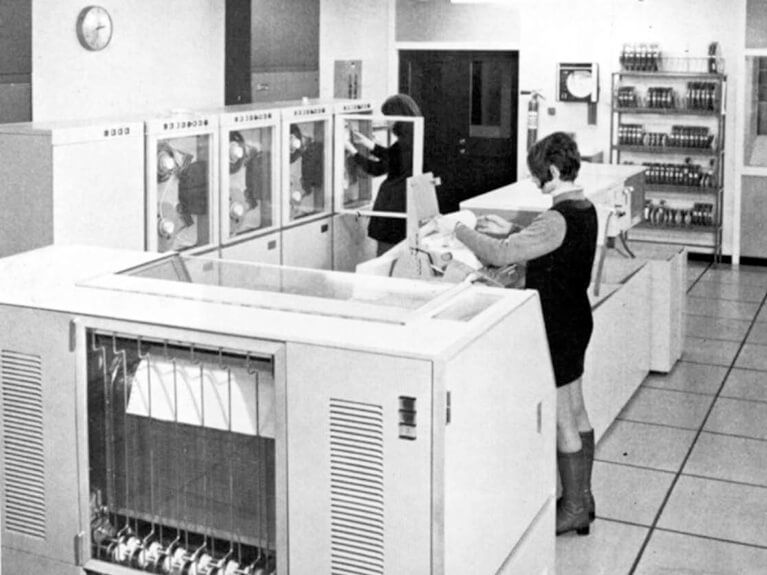 Student beside 1960s large computer