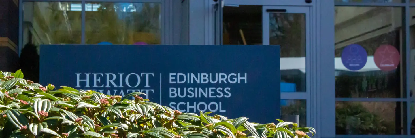 A leafy bush in front of the Heriot-Watt Edinburgh Business School entrance and sign.
