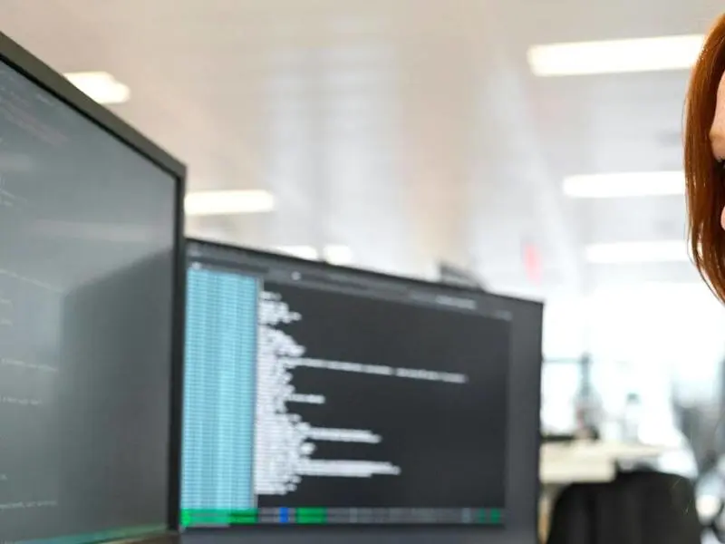 A woman working on a computer looks intently at the screen.