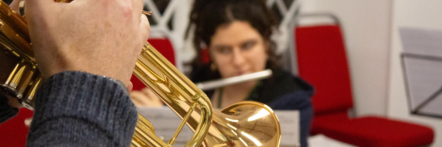 A brass trumpet in a room with red chairs.