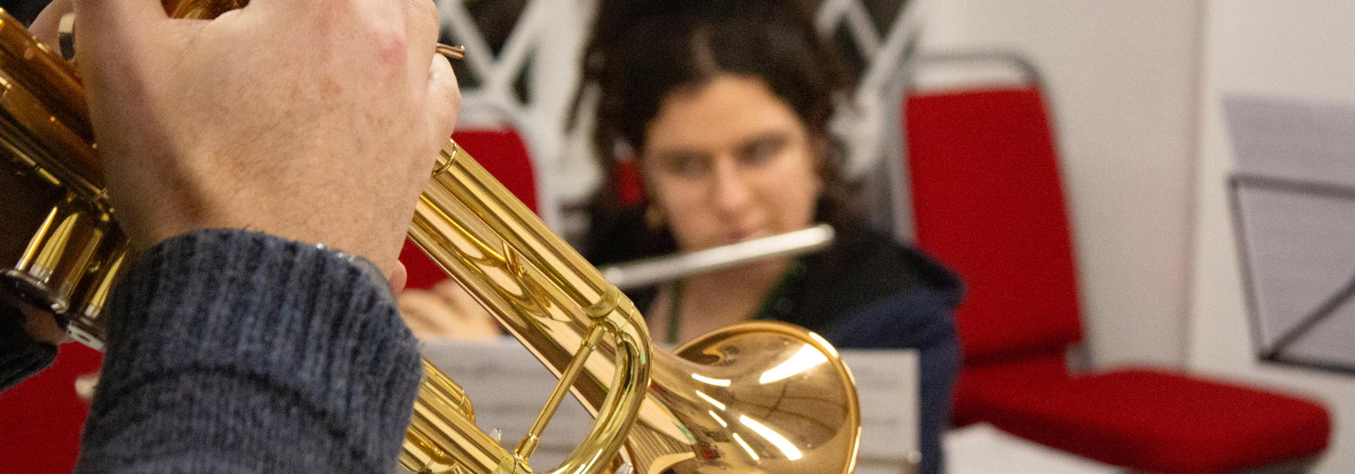 A brass trumpet in a room with red chairs.
