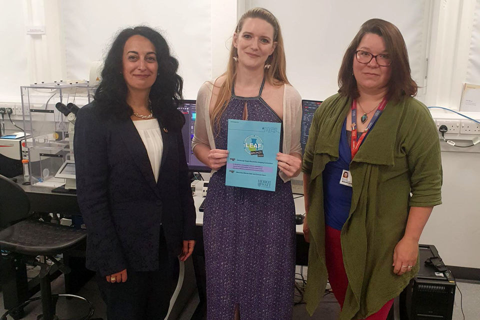 Presentation of the first LEAF certificate by Professor Mercedes Maroto-Valer, Deputy Principal for Global Environmental Sustainability and Anna Clark, Sustainability Strategy Coordinator, to ESRIC Facility Manager, Jessica Valli Professor Mercedes Maroto-Valer, Jessica Valli holding the LEAF award, and Anna Clark