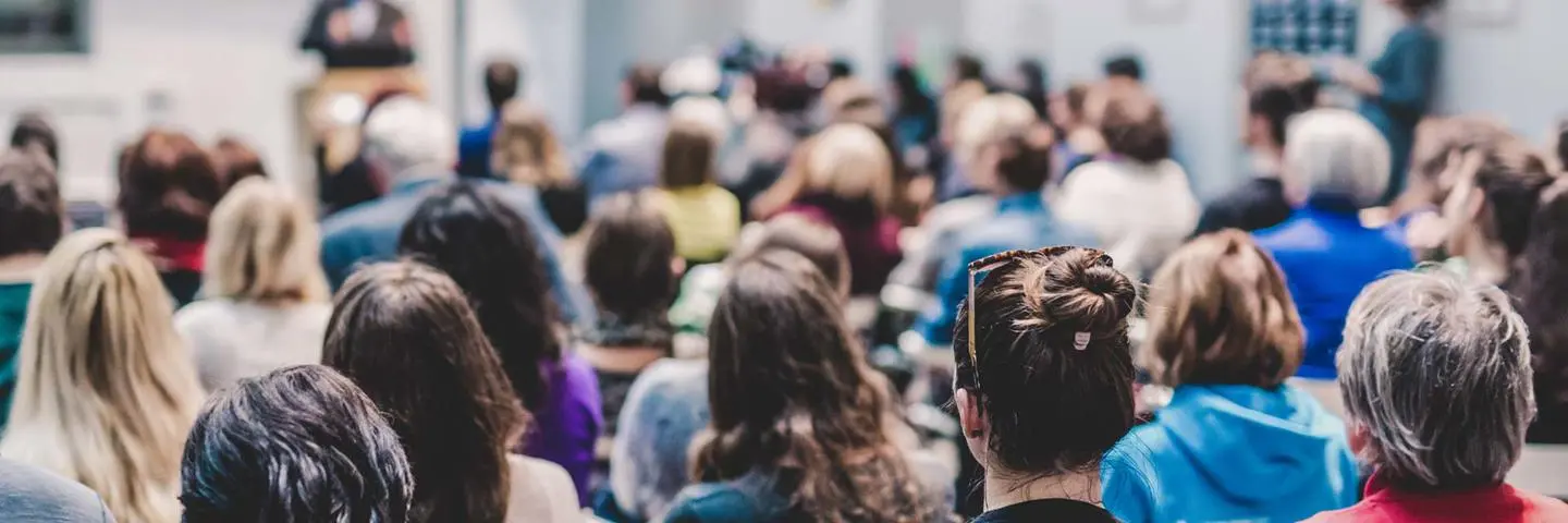 Crowd of people sitting in attendance at an event.