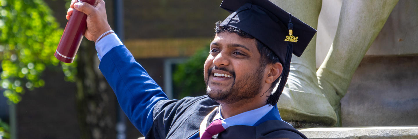 Graduate smiling and waving degree