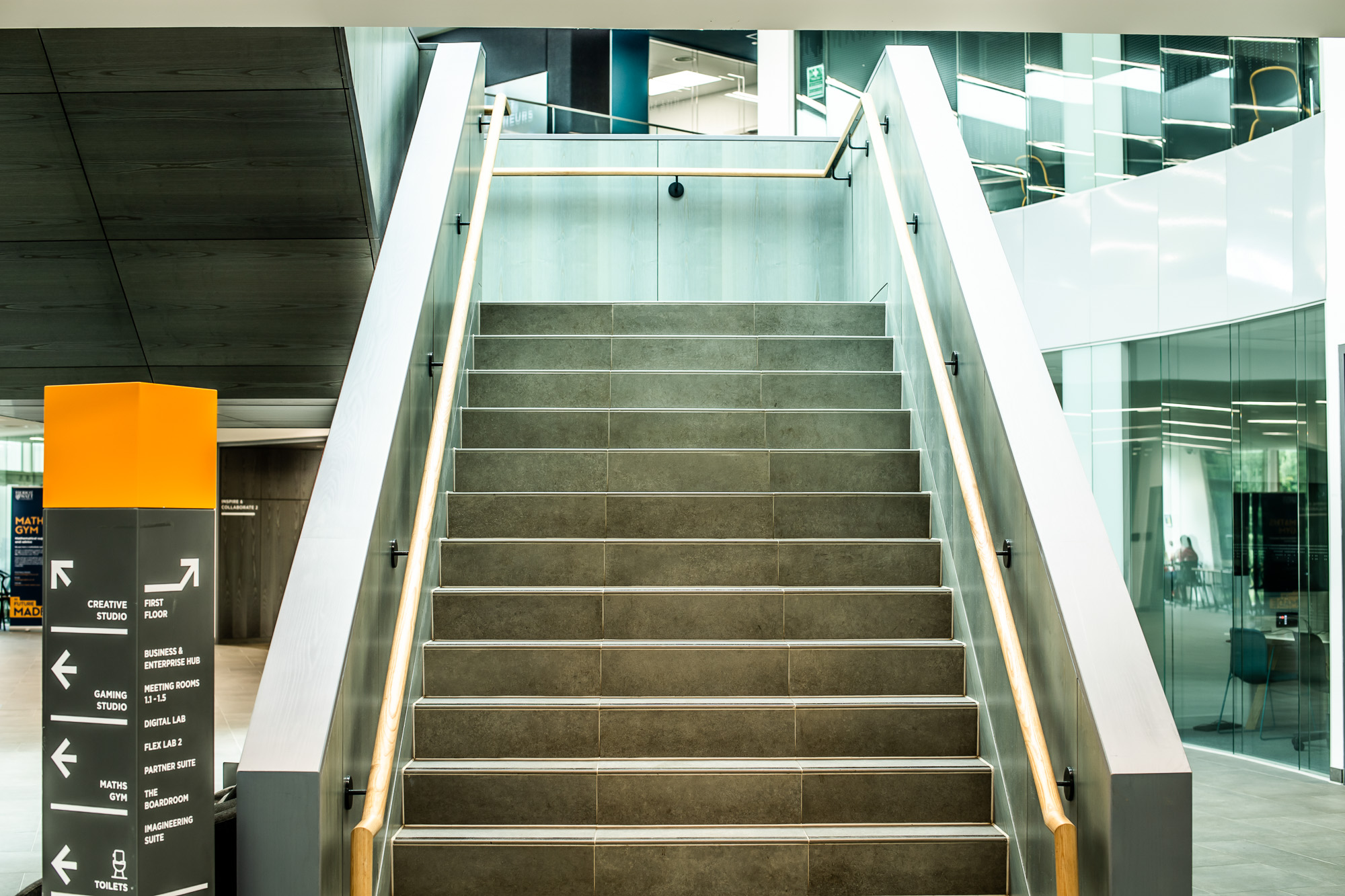 Stairs leading upwards with rails on either side, and a clear signpost to the left of the stairs.