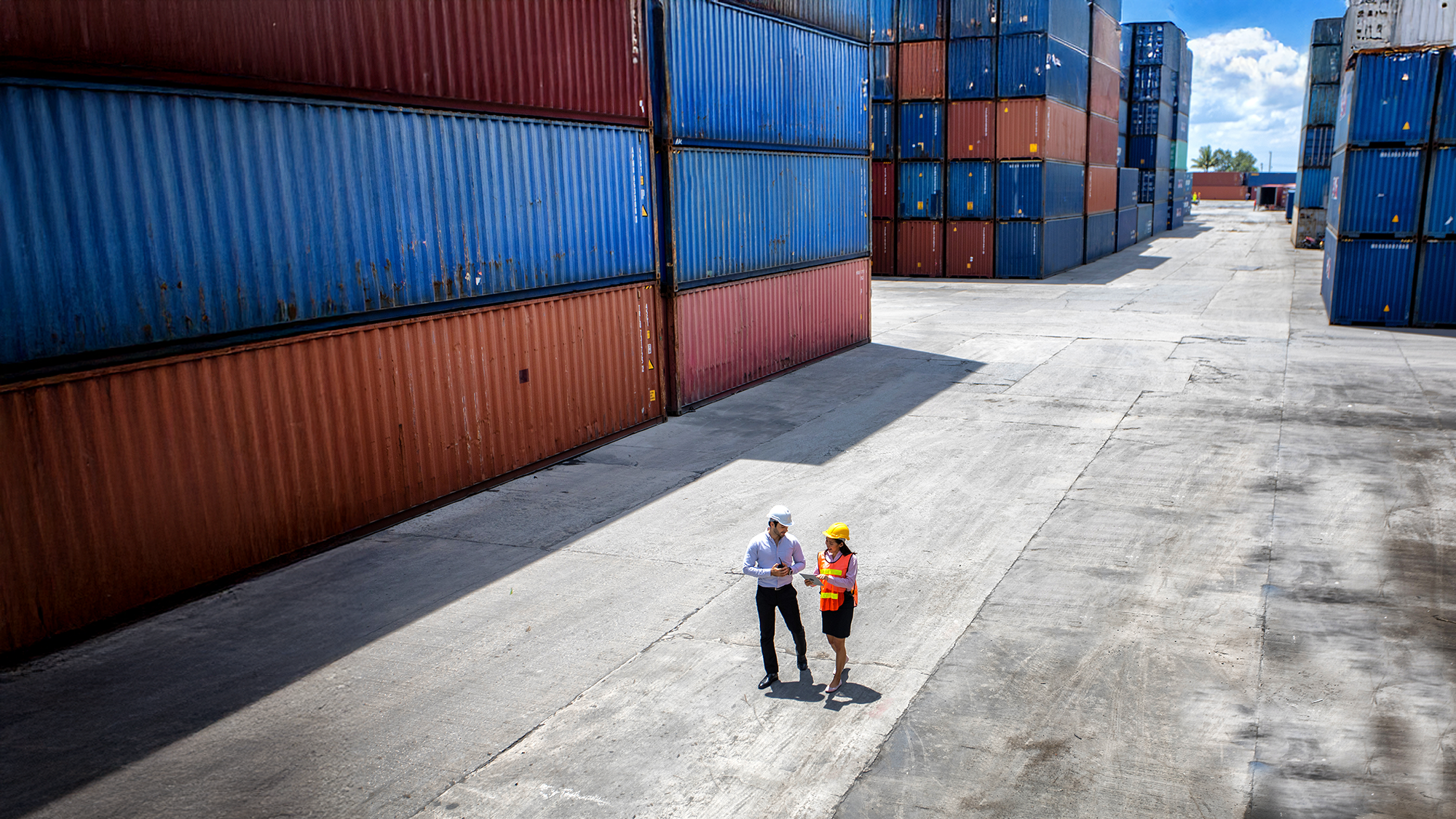 Two logistics managers walking through yard of loading containers.