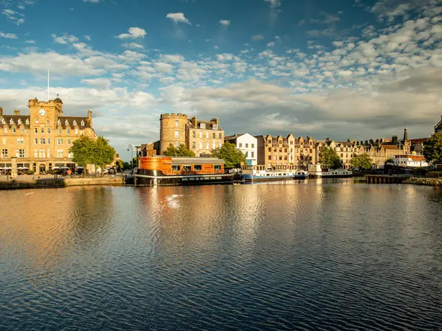 Old buildings and boats line the sides of an expanse of water in Leith.