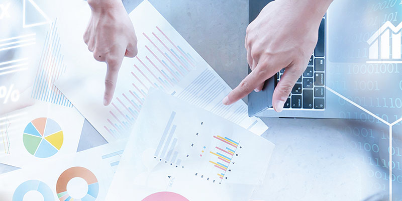 Hands pointing towards printed financial charts and metrics