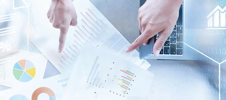 Hands pointing towards printed financial charts and metrics