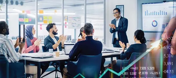 A group of business people sit and applaud in a meeting room