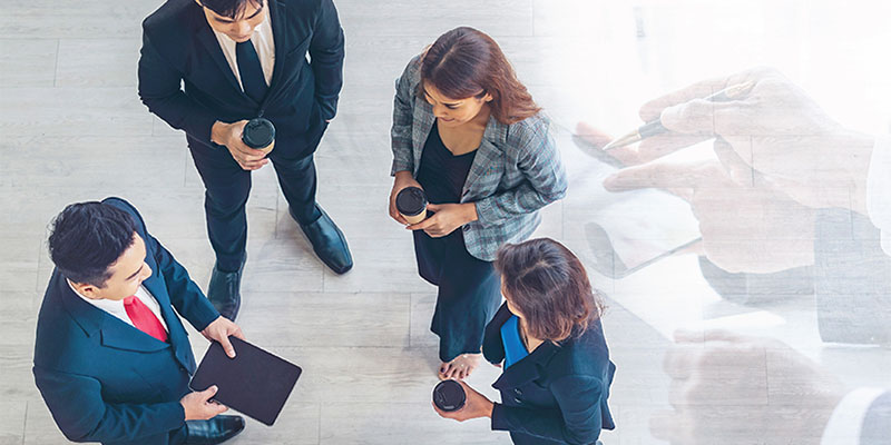 A group of people in business clothes have a stand up coffee meeting