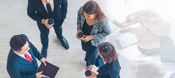A group of people in business clothes have a stand up coffee meeting