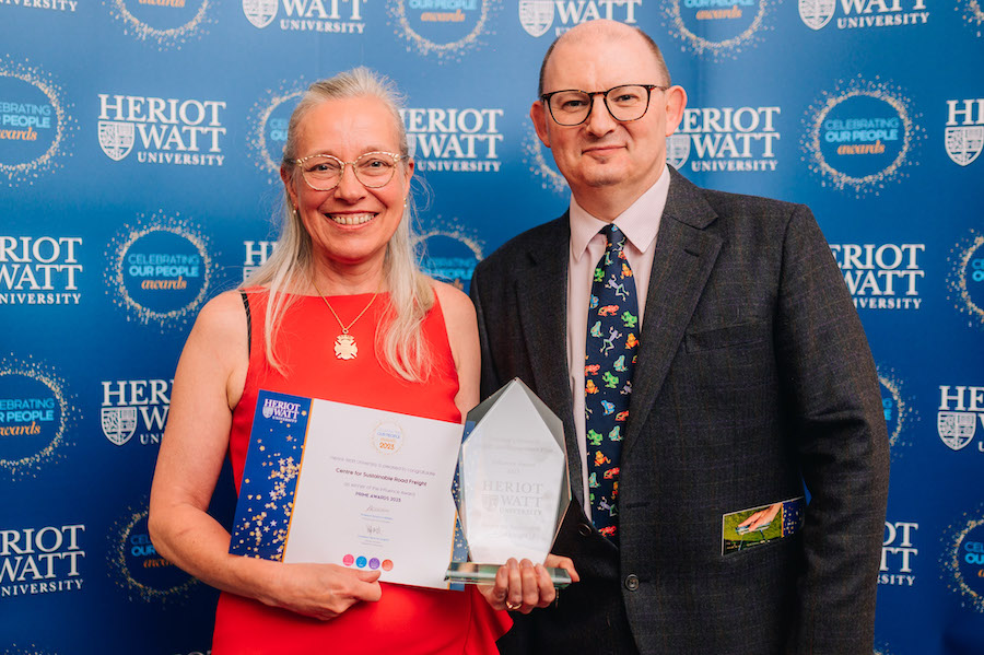 Dr Janey Andrews receiving the Influence award from Prof Marc Desmulliez, for the Centre for Sustainable Road Freight Teo individuals smiling as they receive an award and certificate.