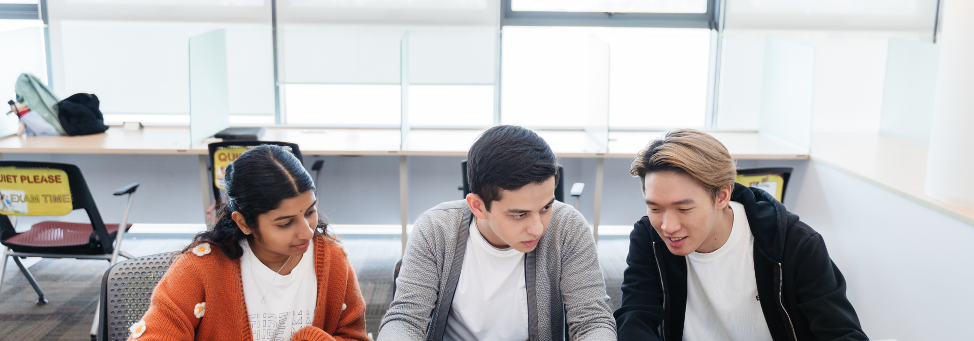Three students sitting at a desk.
