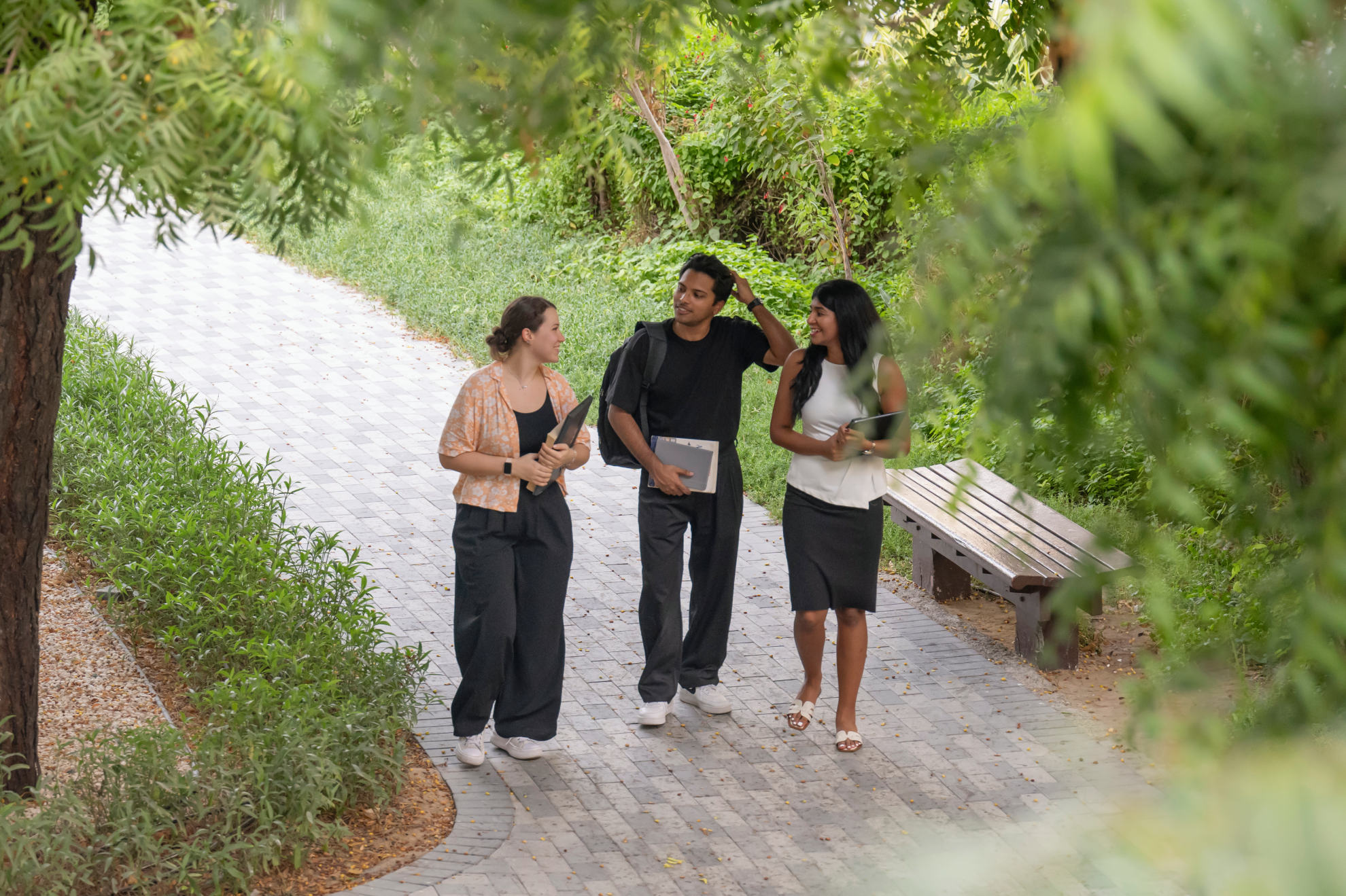 Three individuals walking outside in a park.
