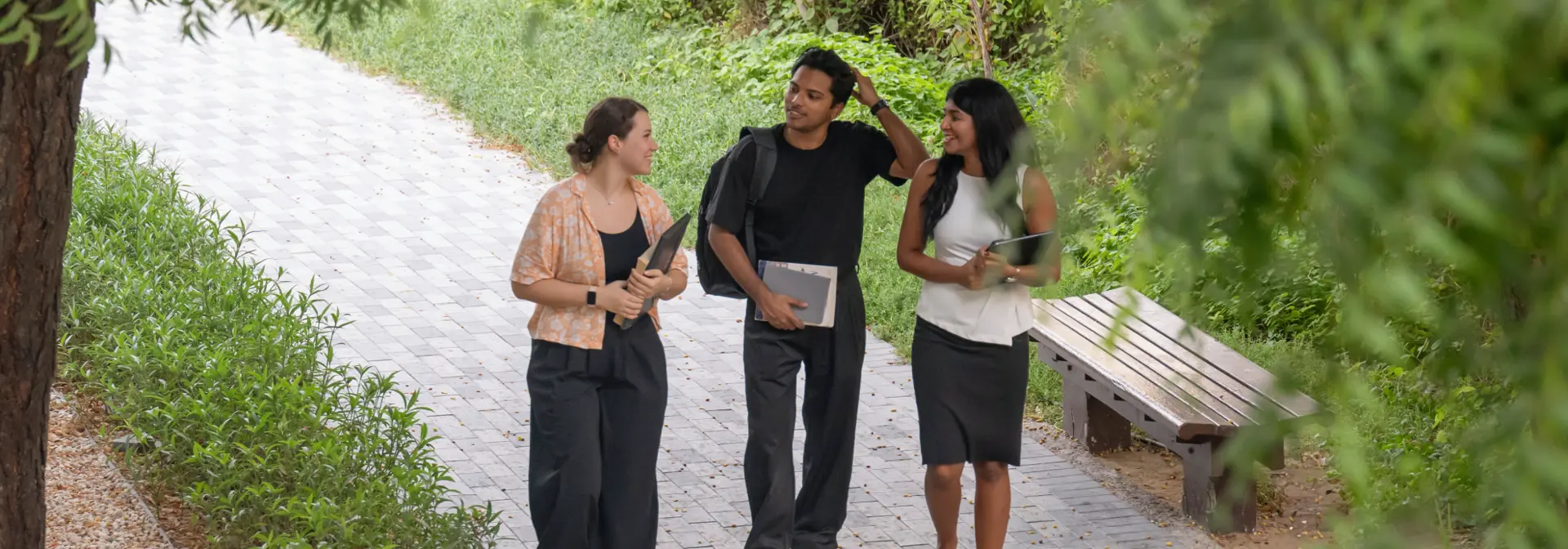 Three individuals walking outside in a park.
