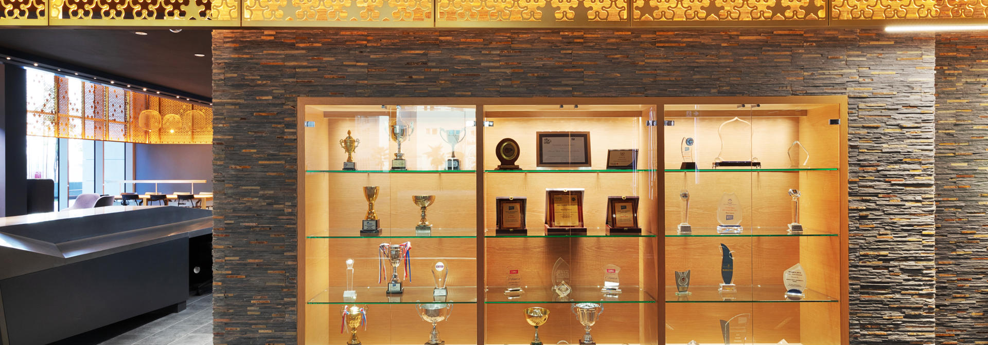 A wooden brown display case with trophies on shelves.