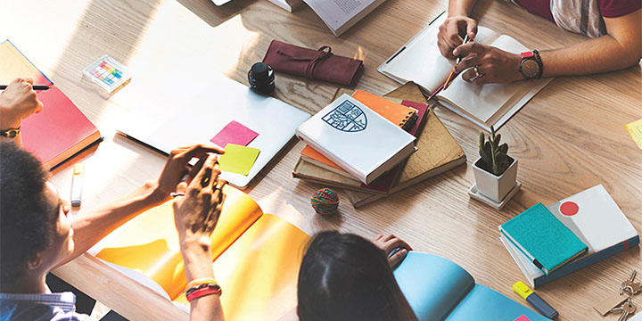 A group of students seated around a table of books