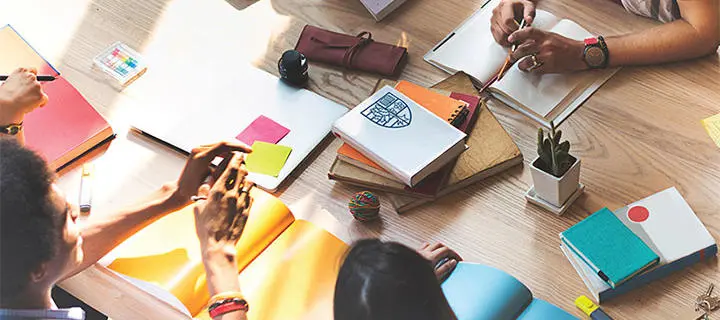 A group of students seated around a table of books