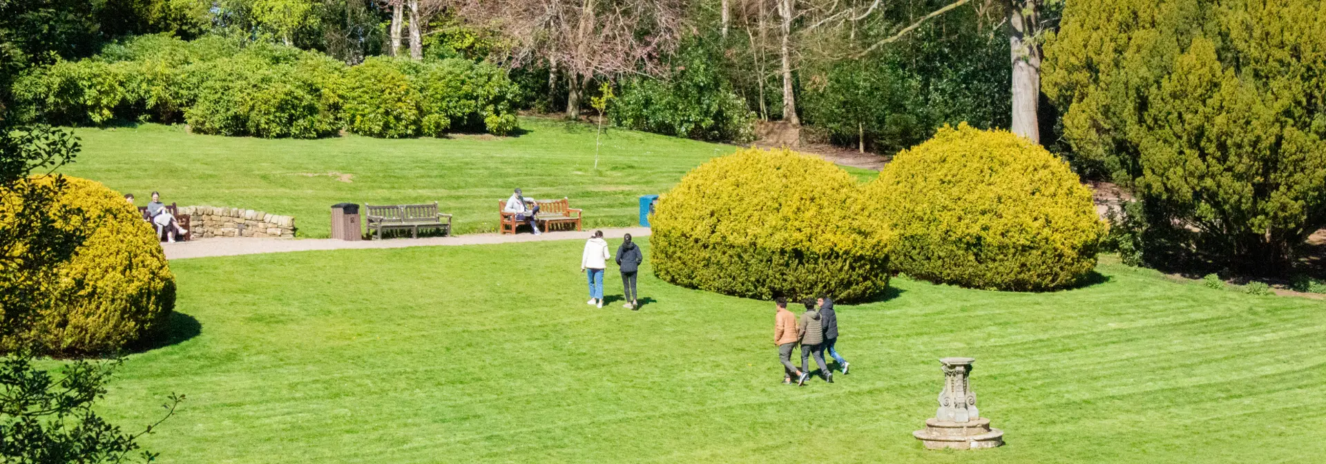 Picture of students walking across a lawn on a sunny day.