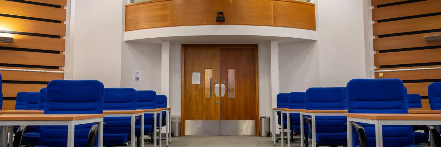 An empty room full of blue chair and desks set up for an assessment.