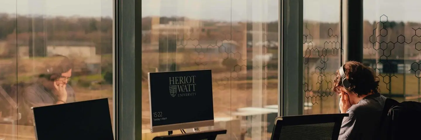 Student working at a desk infront of a window in the Edinburgh campus.