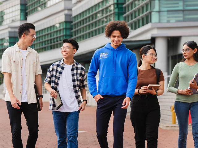 Five students walking on Heriot-Watt University Malaysia campus.