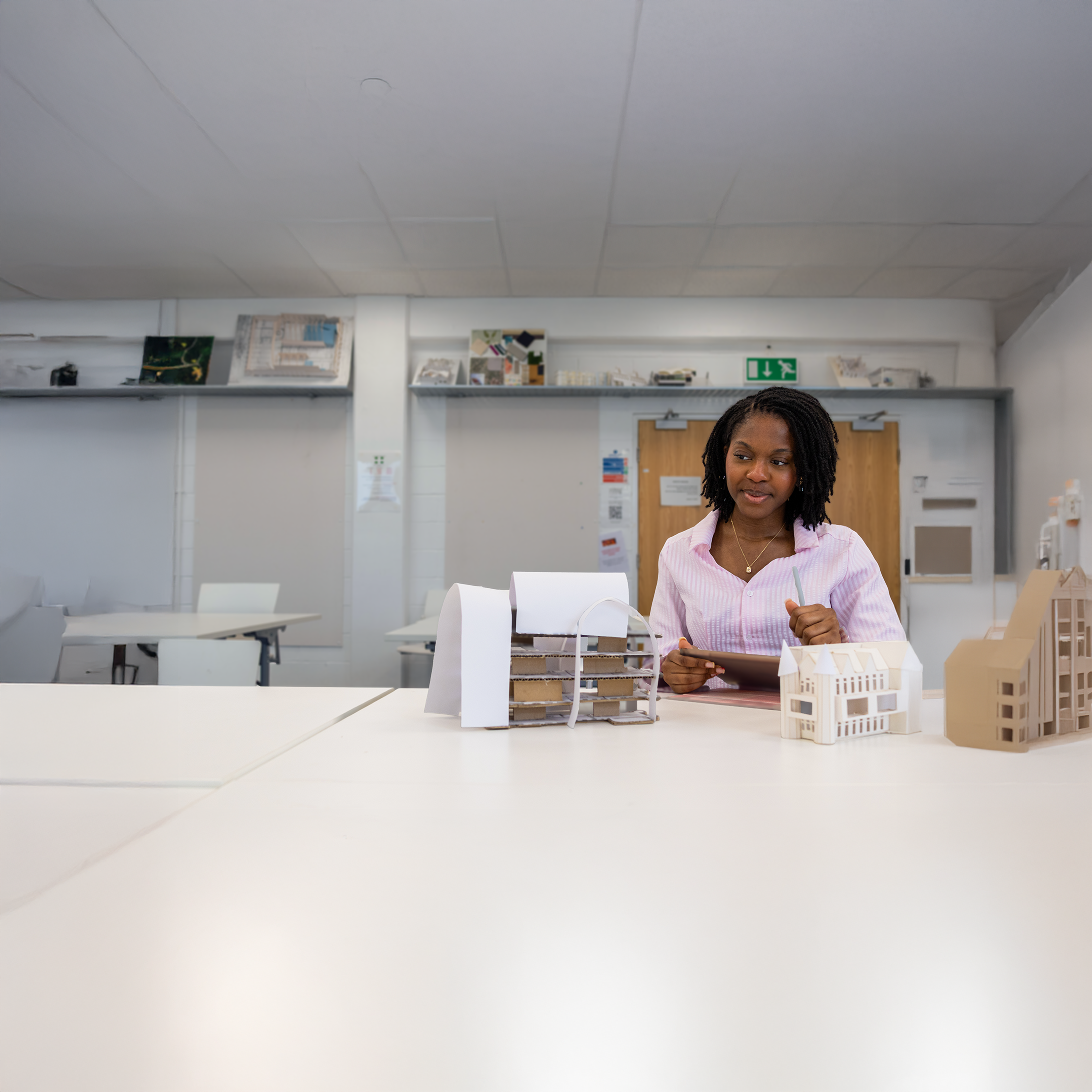 Naomi sitting in a class with architectural models on her desk