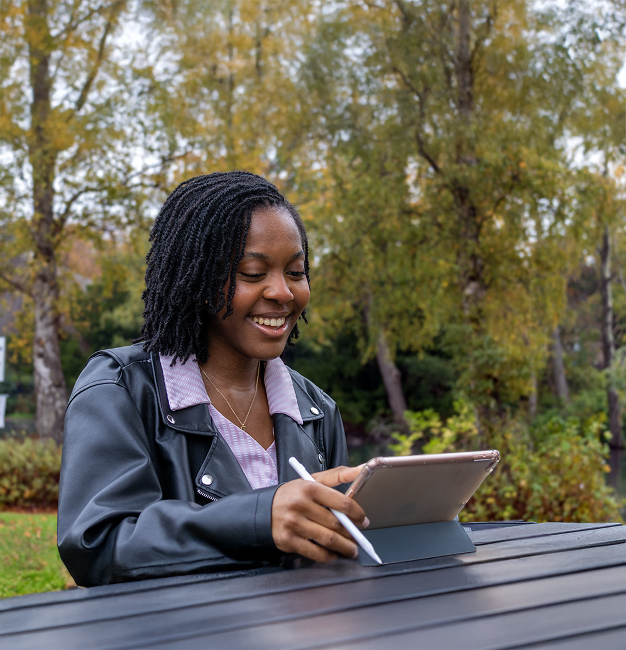Naomi, a current student, working on an ipad outside at a bench on the Edinburgh campus.