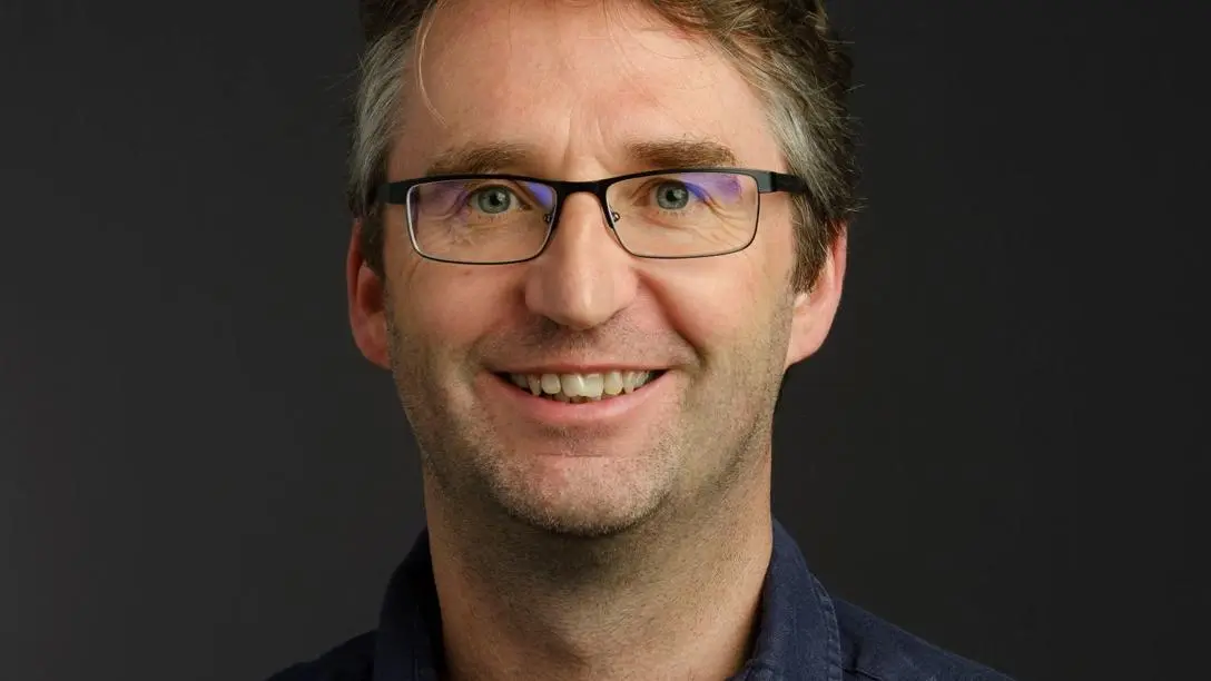 A white man with glasses and short brown hair smiling