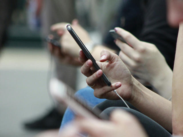 Commuters scrolling through their phones. Photo by Robin Worrall on Unsplash.