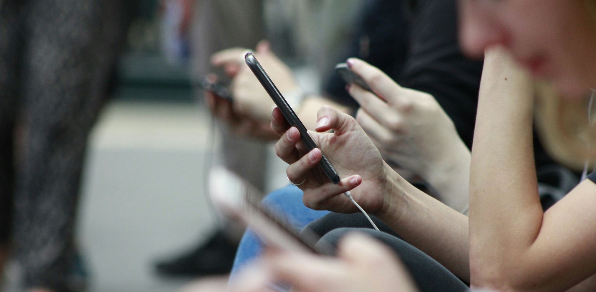 Commuters scrolling through their phones. Photo by Robin Worrall on Unsplash.