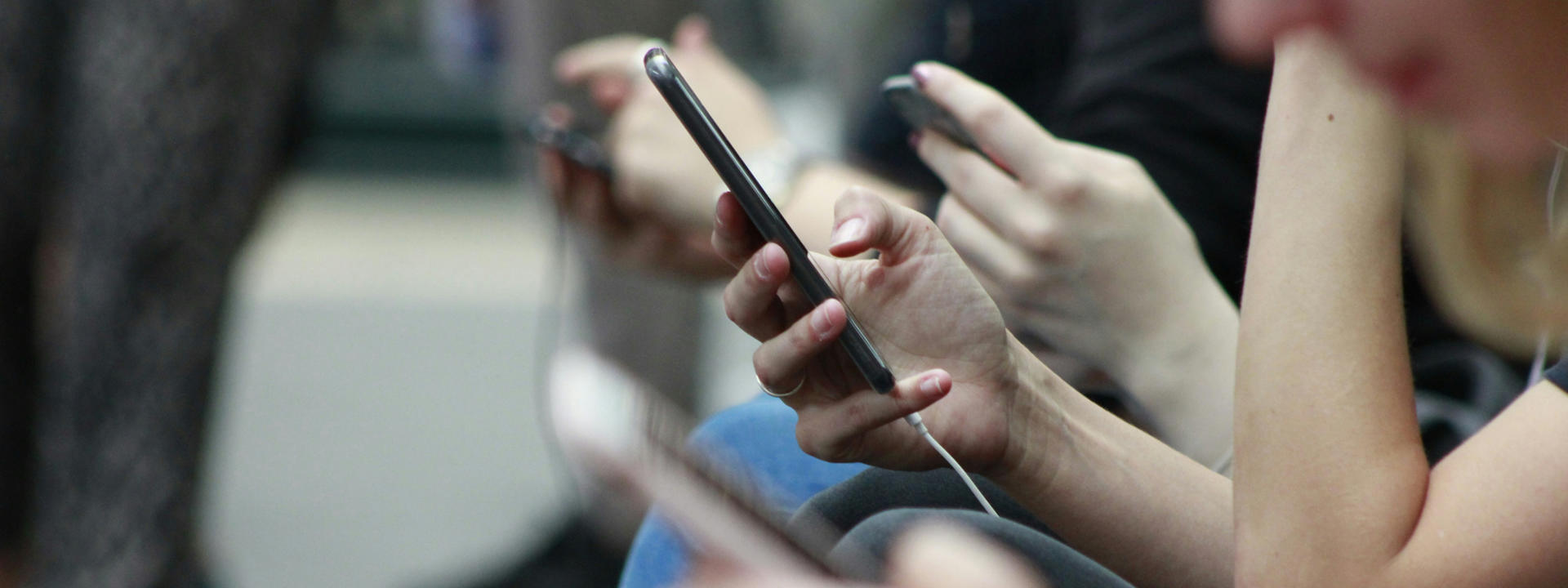 Commuters scrolling through their phones. Photo by Robin Worrall on Unsplash.