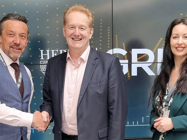 Three people stand in the Heriot-Watt GRID building agreeing on an Memorandum of Understanding