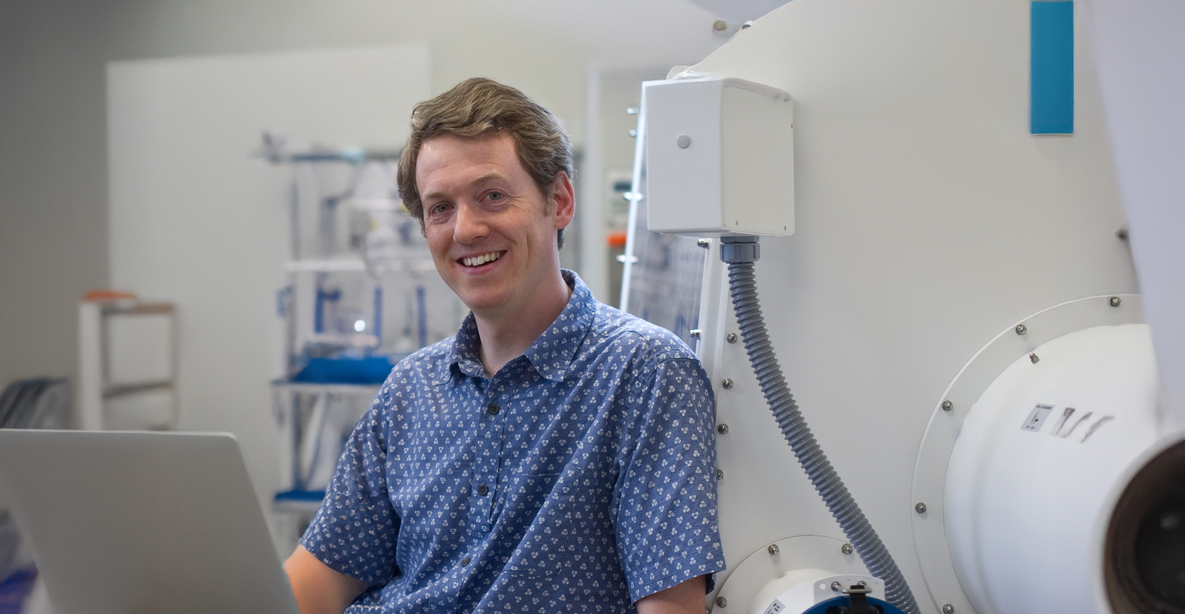Assistan Professor Stephen Mansell head/shoulders shot, facing camera, with a laptop in the lab.