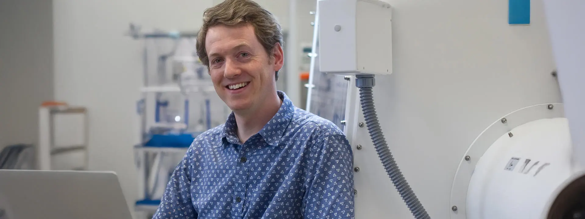 Assistan Professor Stephen Mansell head/shoulders shot, facing camera, with a laptop in the lab.