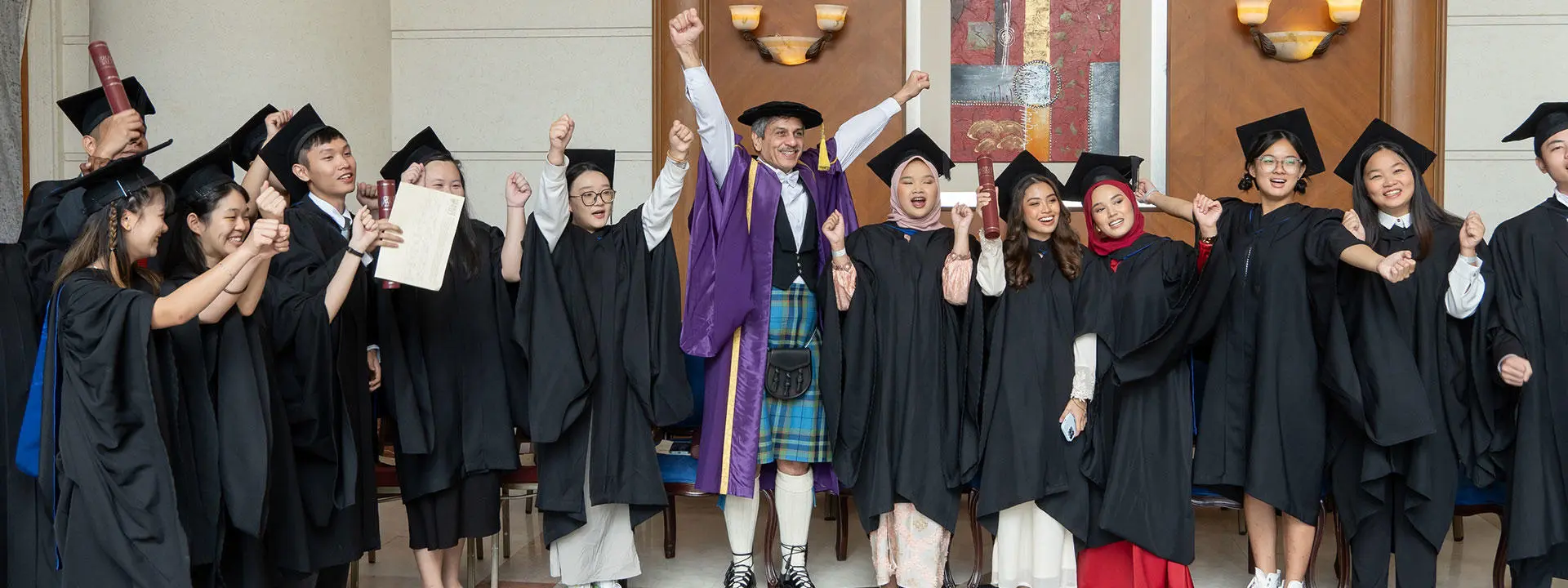 A group of graduates in caps and gowns smiling together for a celebratory photo.