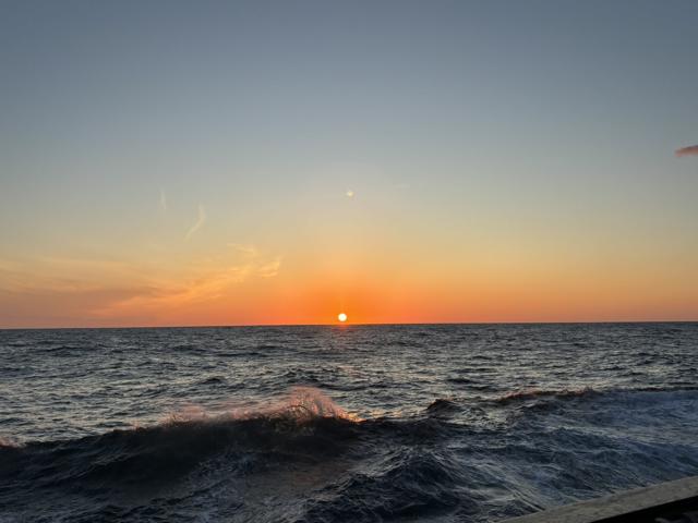 The image shows a beautiful sunset over the ocean. The sun is partially below the horizon.