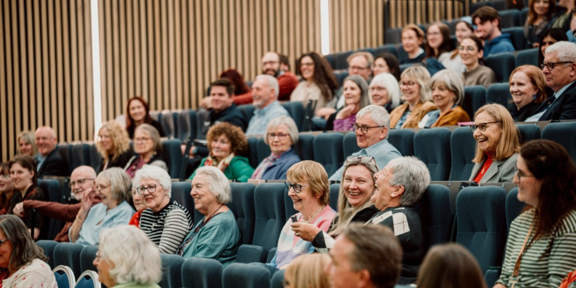Picture displays a cohort of older adults, laughing and talking during a seminar at Heriot-Watt.