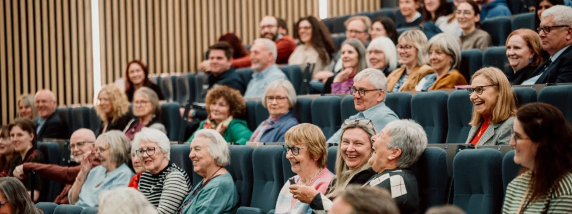 Picture displays a cohort of older adults, laughing and talking during a seminar at Heriot-Watt.