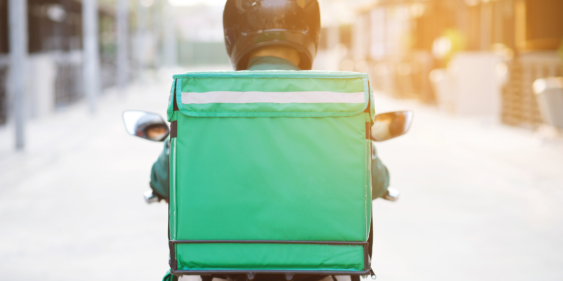 Courier on bike with green food delivery bag.