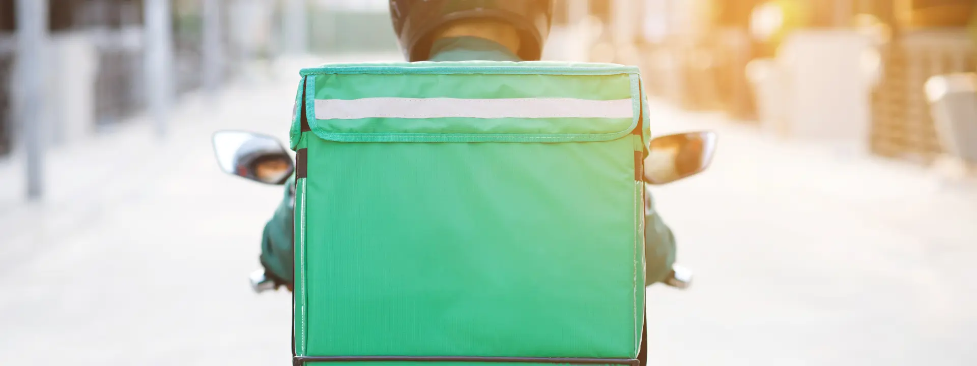 Courier on bike with green food delivery bag.