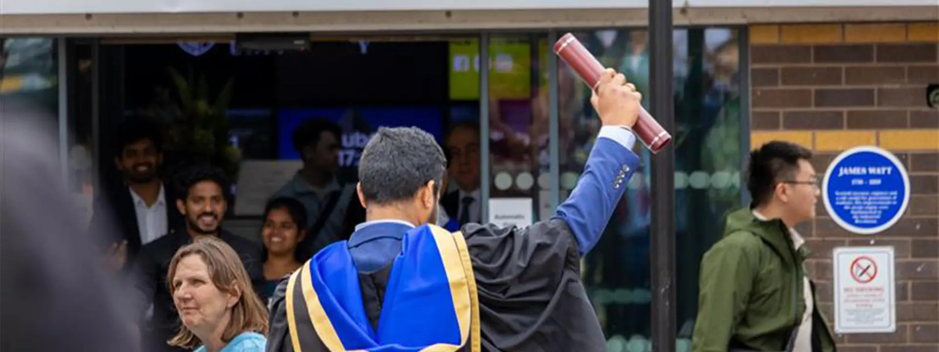 Student holding a scroll in the air.